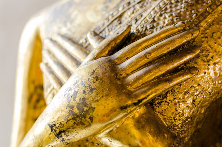 Goldene Buddhastatue mit auf der Brust ruhenden Haenden